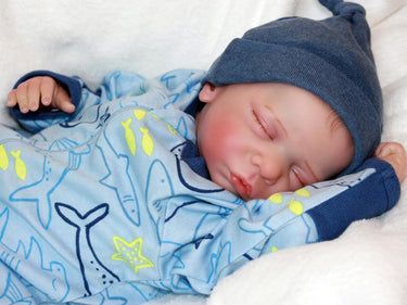 A baby doll resting on a soft blanket, showcasing its delicate features and clothing.